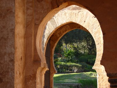 Keyhole-shaped archways revealing luscious green garden Chellah, Rabat, Morocco, Africa