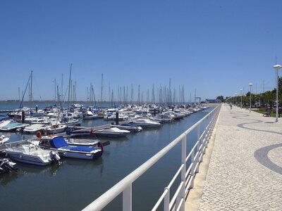 Boats lined up next to each other in port with stone pathway adjacent, Spain