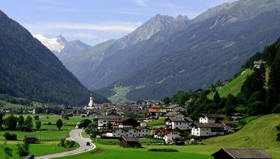Stubaital valley town nestled between mountains and green hills with pine trees, Stubai Alps, Austria